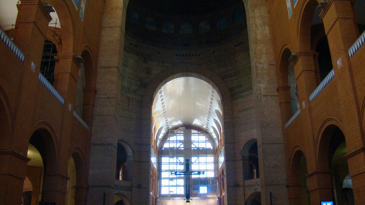 Nave da Basílica de Aparecida com o teto branco de placas e grande janela ao fundo