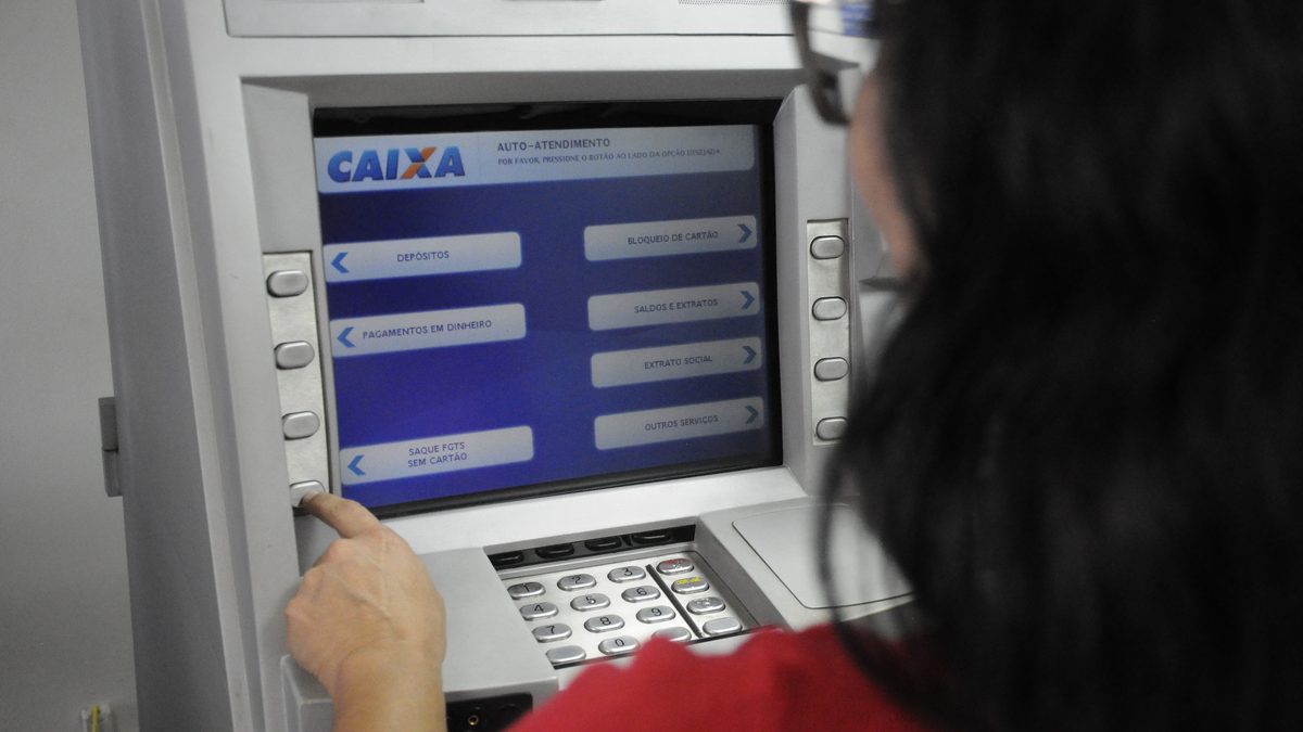 Mulher usa caixa eletrônico da Caixa para consultar o benefício