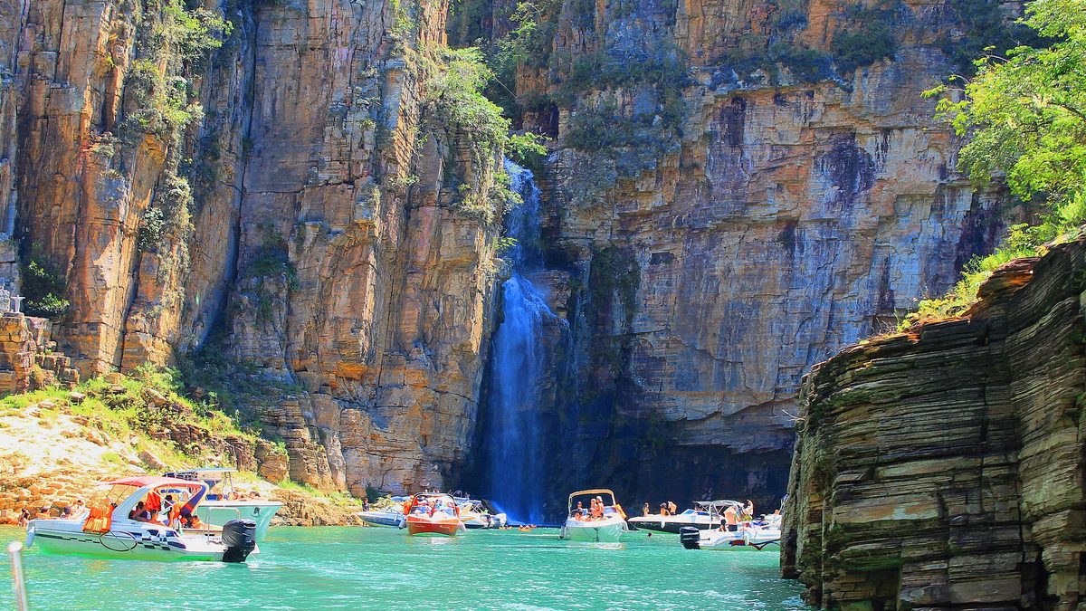 Lanchas diante de cascata entre paredões de rocha nos cânions do Lago de Furnas, em Capitólio