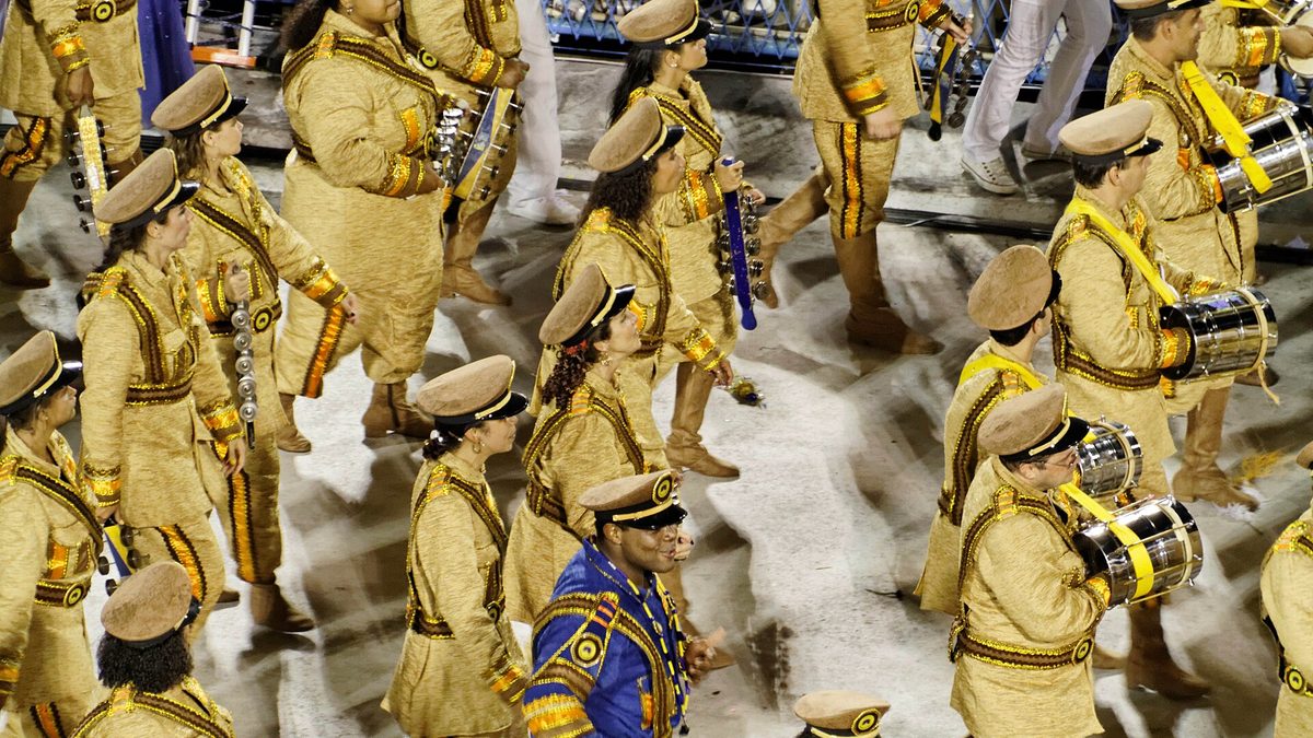 Ritmistas fantasiados de dourado tocam na bateria de escola de samba na Sapucaí