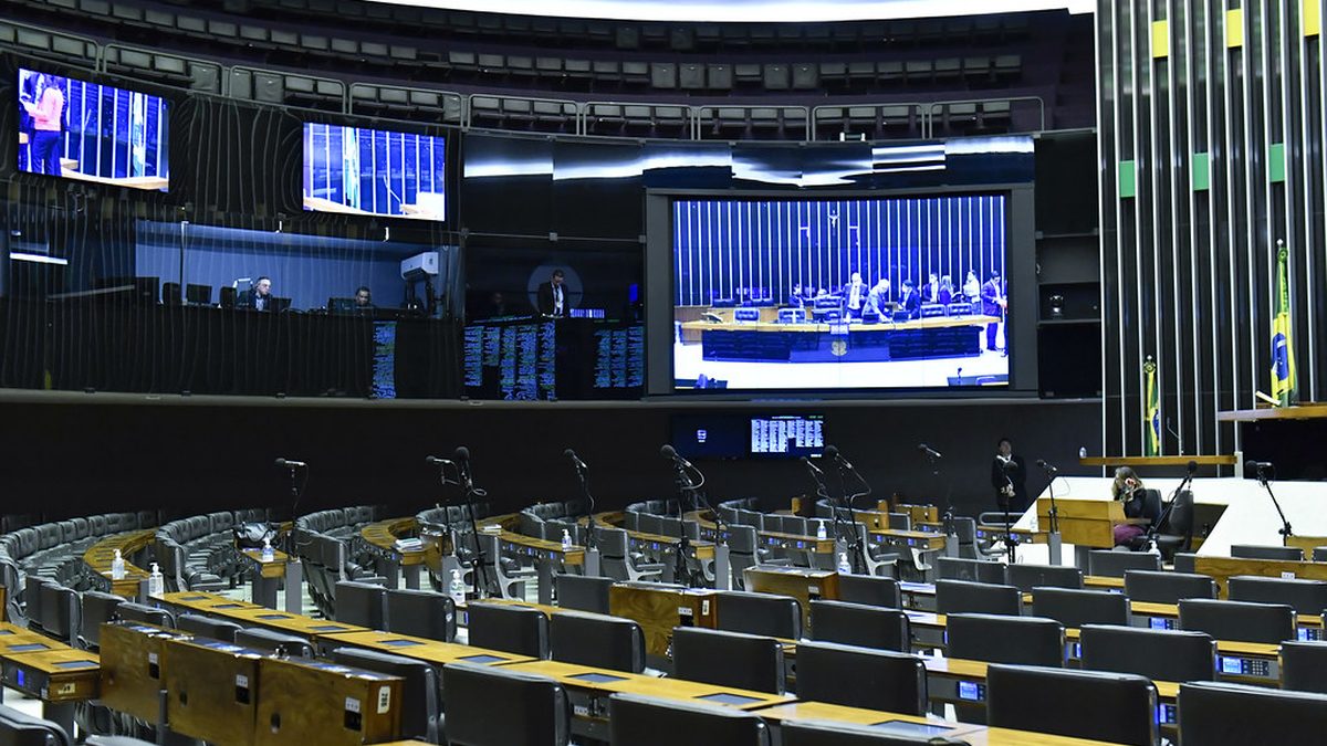 Plenário da Câmara dos Deputados com poltronas vazias e telões, em Brasília