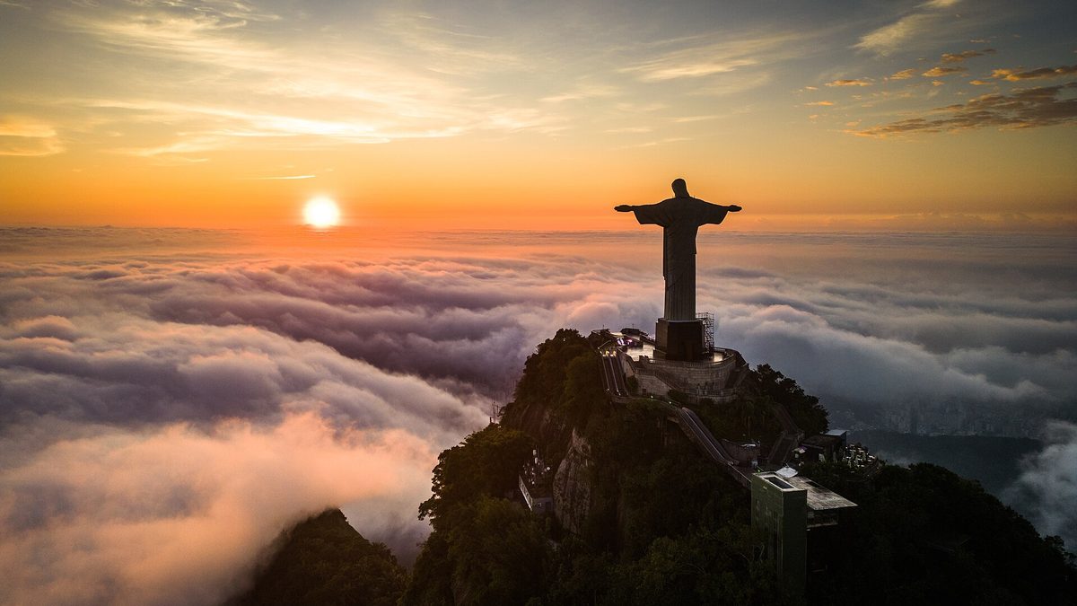 Cristo Redentor no alto do Corcovado ao nascer do sol, acima de um mar de nuvens