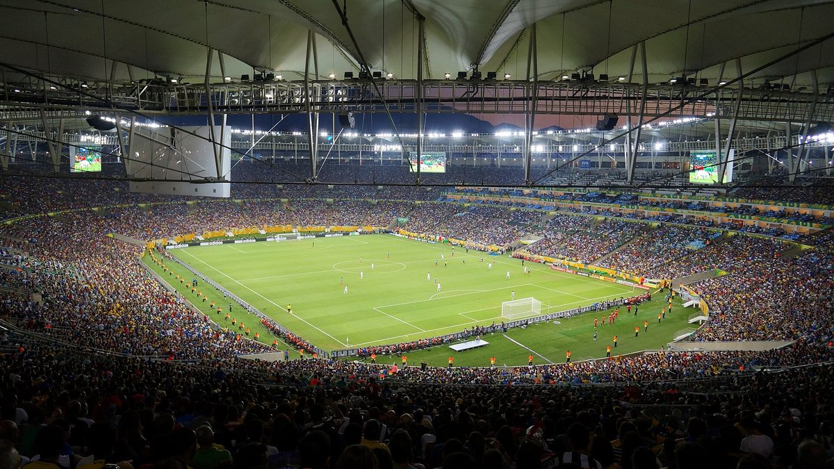 Arquibancadas cheias e gramado iluminado do Maracanã em jogo à noite, no Rio de Janeiro