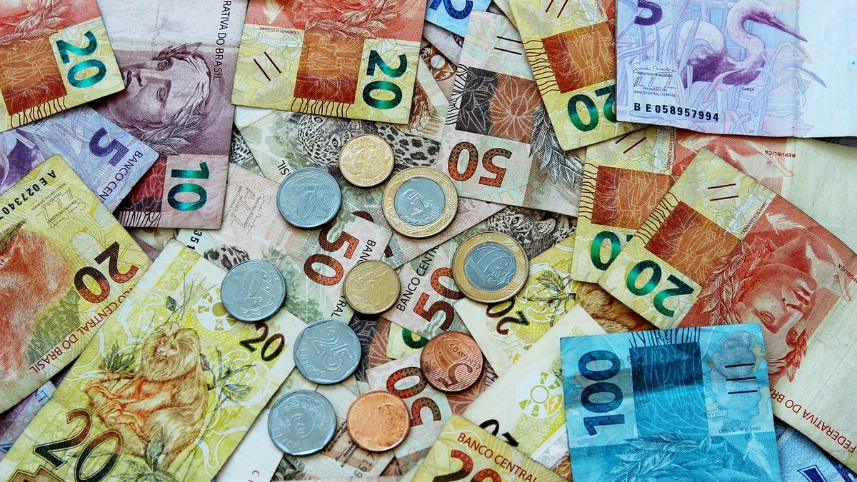 Cédulas e moedas de real espalhadas sobre uma mesa