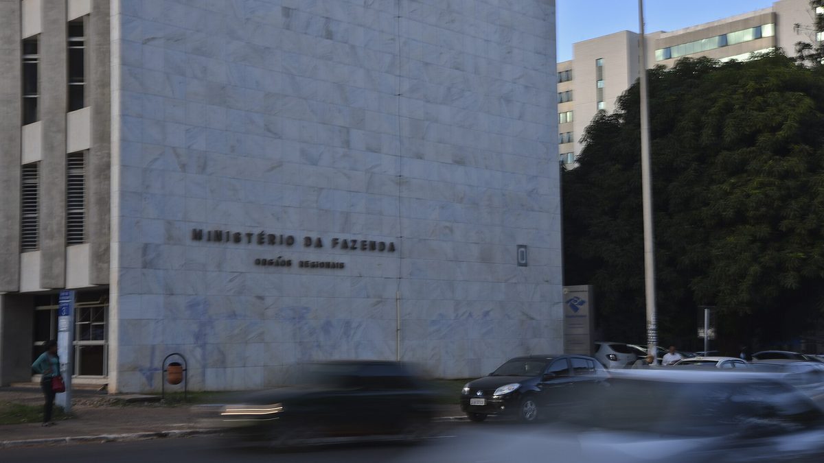 Fachada de mármore de prédio do Ministério da Fazenda com carros passando, em Brasília