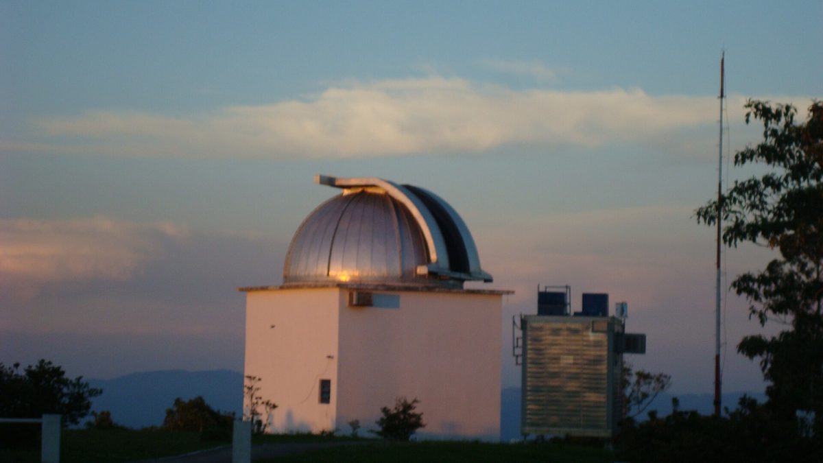 Cúpula prateada de telescópio ao entardecer no Observatório do Pico dos Dias, em Minas Gerais