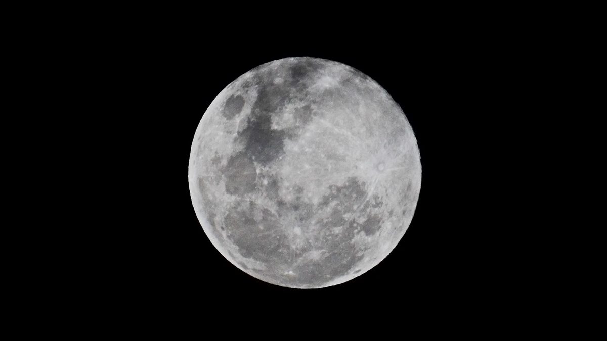 Lua cheia no céu escuro, com crateras e mares lunares visíveis