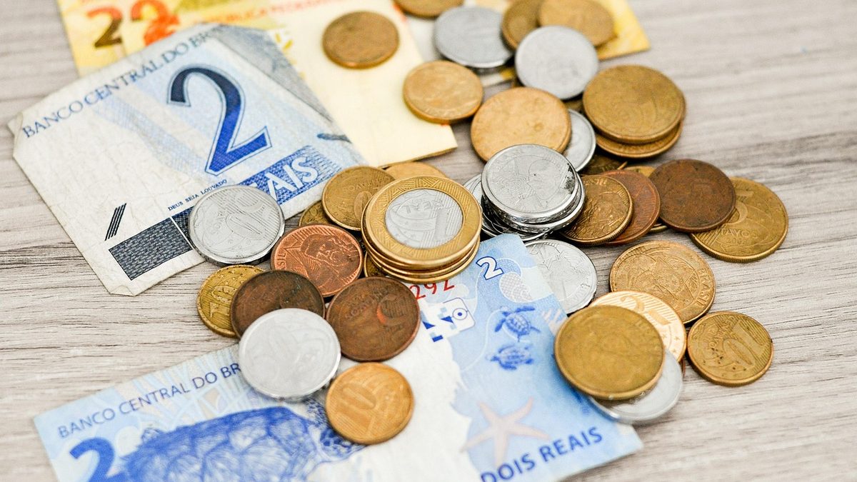 Moedas de real espalhadas sobre cédulas de 2 reais em uma mesa