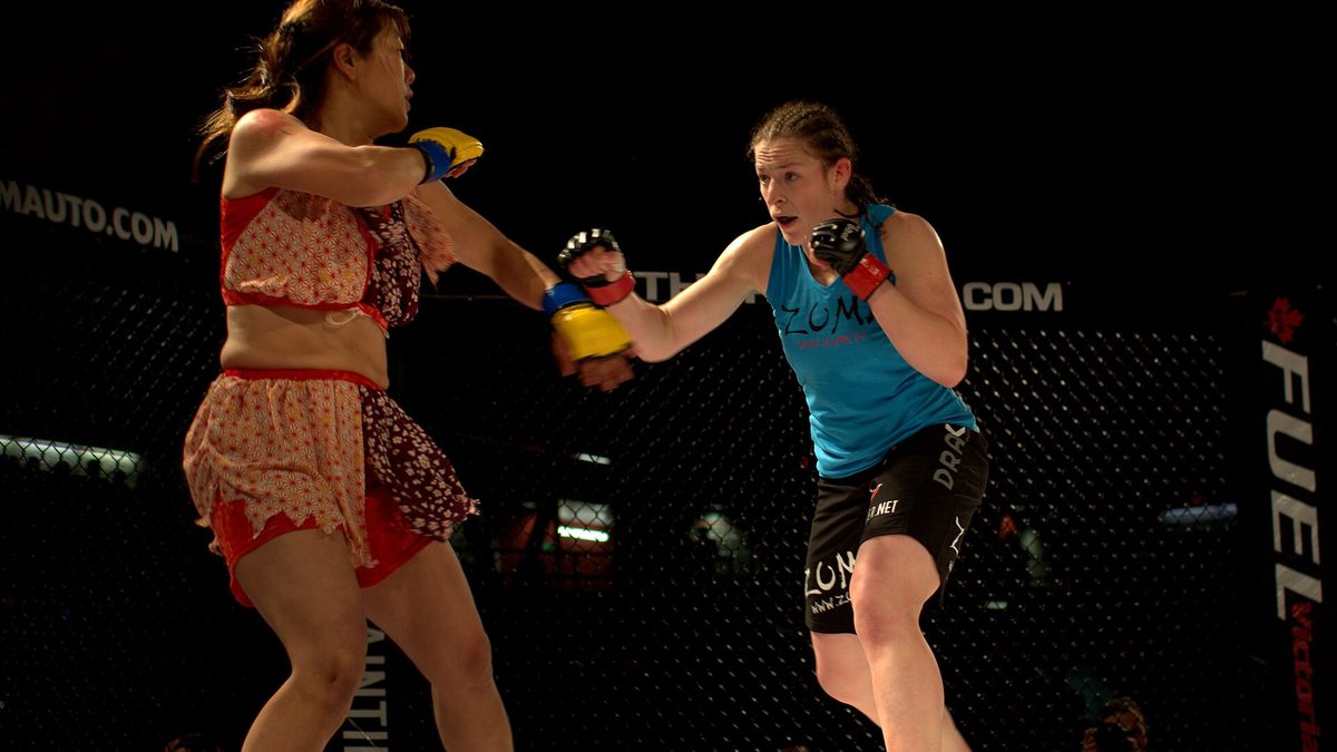 Duas lutadoras de MMA trocam golpes dentro de uma gaiola