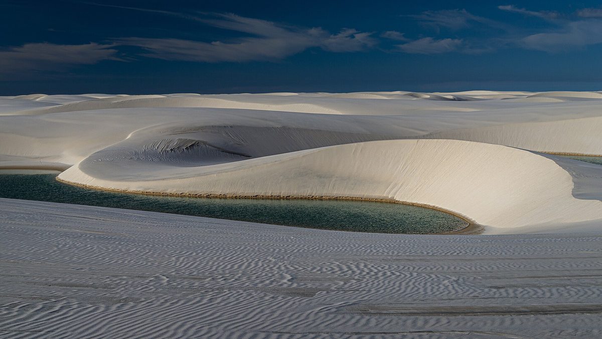 Lagoa de água verde entre dunas brancas nos Lençóis Maranhenses