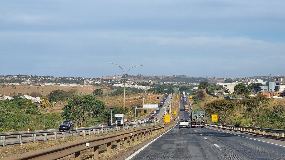 Trecho duplicado da BR-153 em Anápolis (GO), com caminhões e carros e a cidade ao fundo