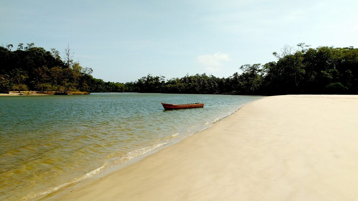 Praia de areia clara com barco ancorado na Ilha de Marajó, no Pará