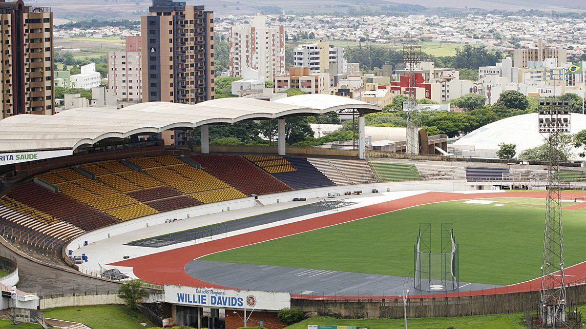 Arquibancadas coloridas, pista de atletismo e gramado do Estádio Willie Davids, em Maringá