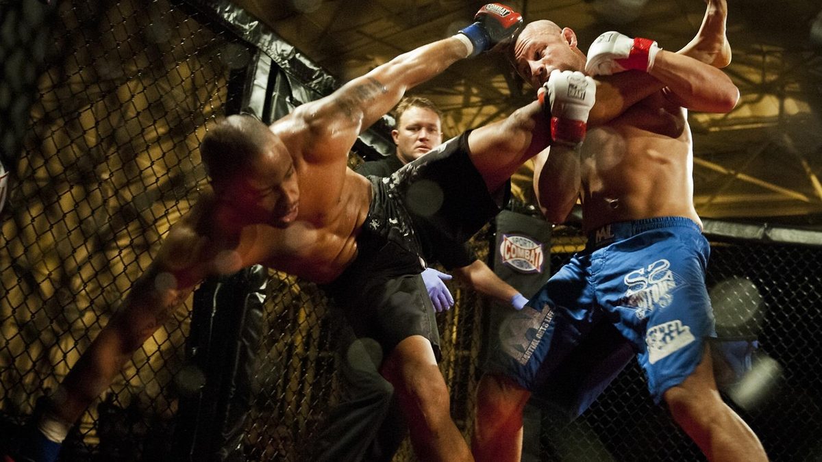 Dois lutadores trocam socos dentro de uma grade de MMA