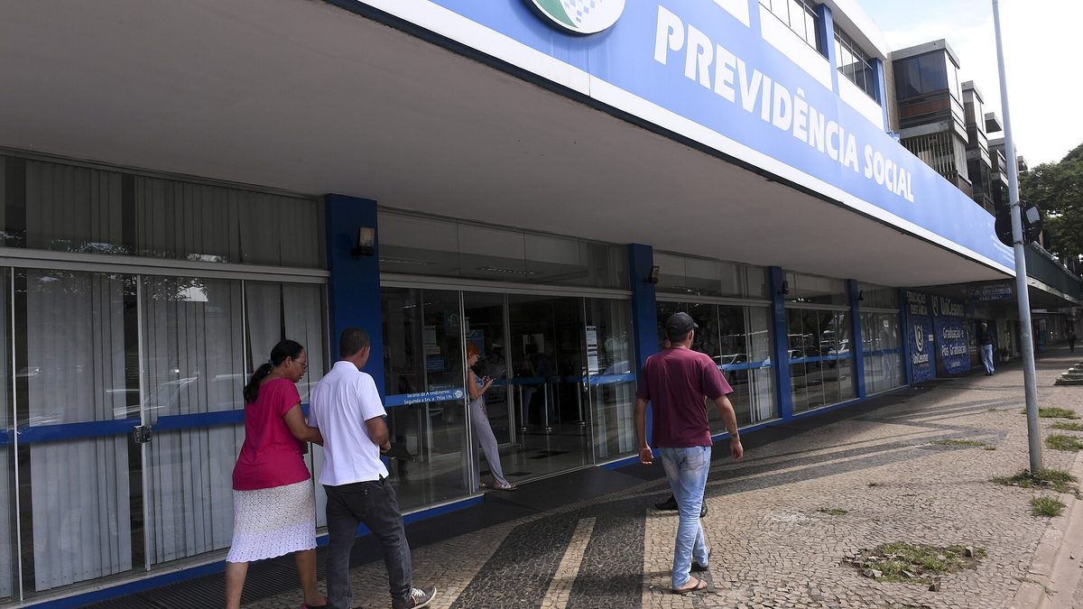 Fachada de agência da Previdência Social com pessoas na calçada