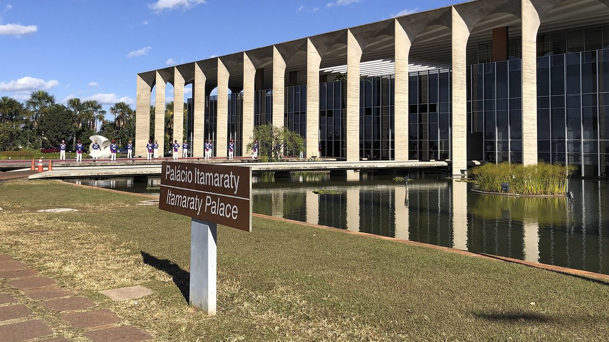Palácio Itamaraty com arcos sobre o espelho d'água e guarda de honra ao fundo, em Brasília