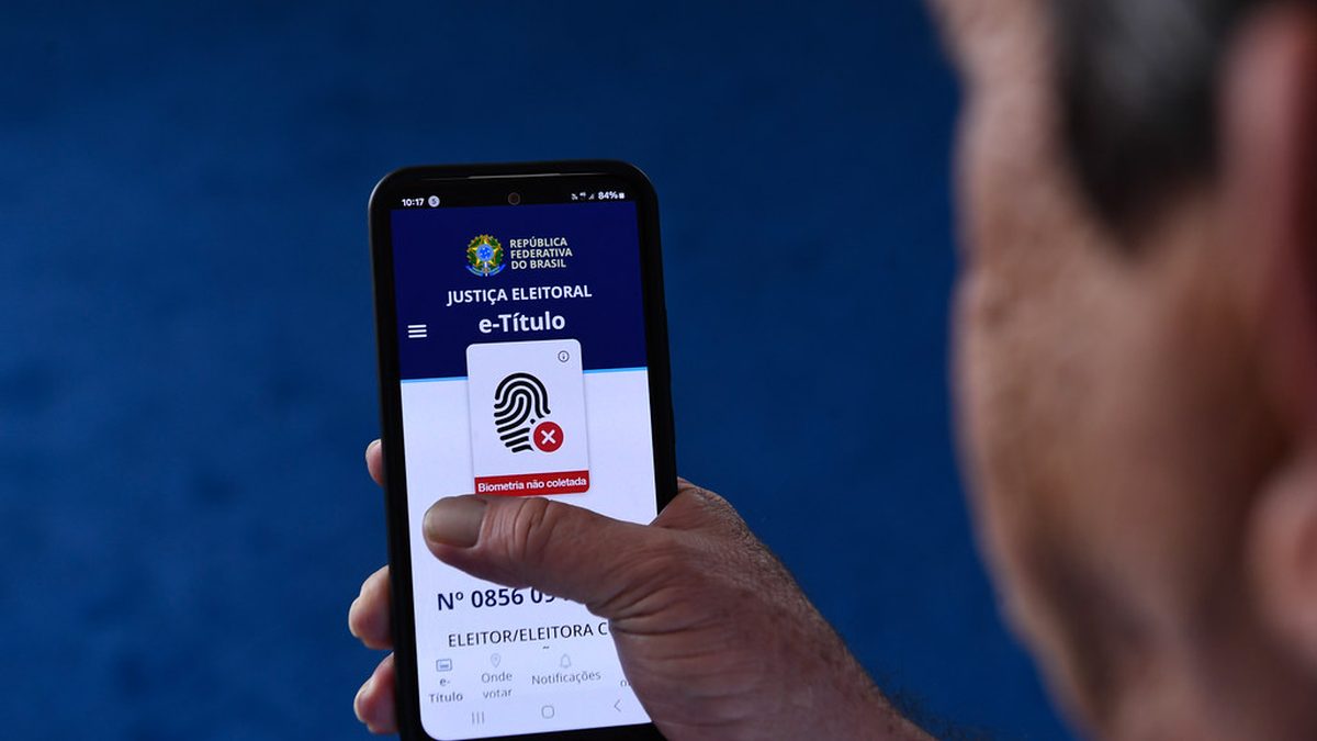Mão segura celular com o aplicativo e-Título da Justiça Eleitoral aberto