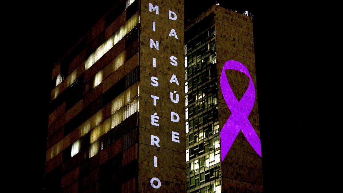 Prédio do Ministério da Saúde iluminado à noite com um laço rosa projetado na fachada