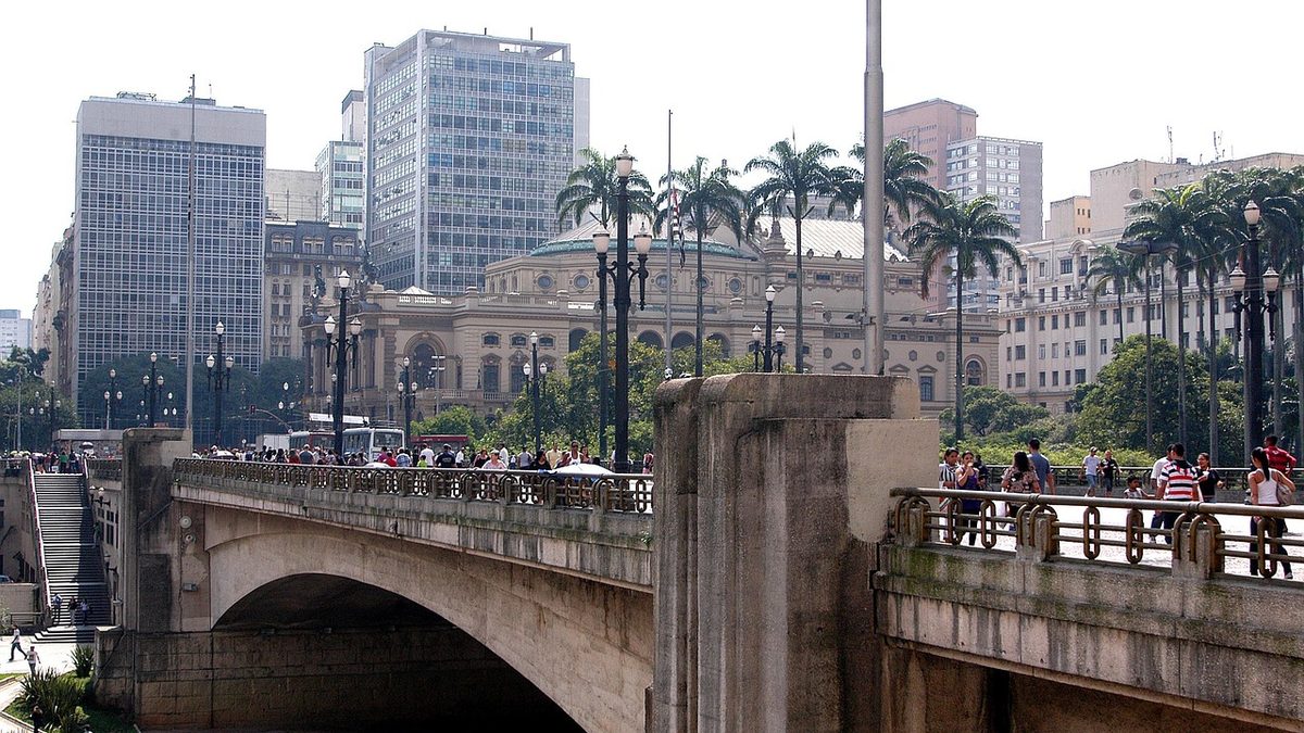 Pedestres no Viaduto do Chá, com o Theatro Municipal ao fundo, em São Paulo