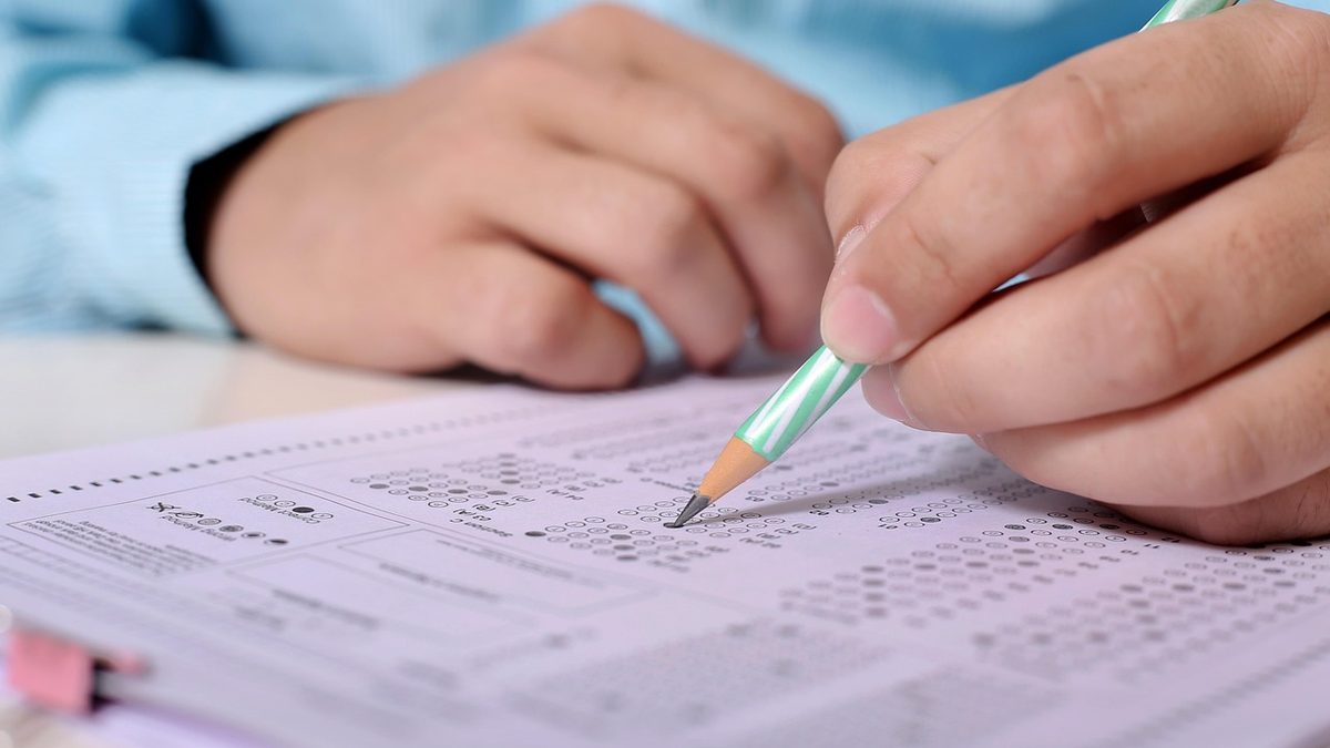 Mão de adulto preenche com lápis o cartão de respostas de uma prova objetiva