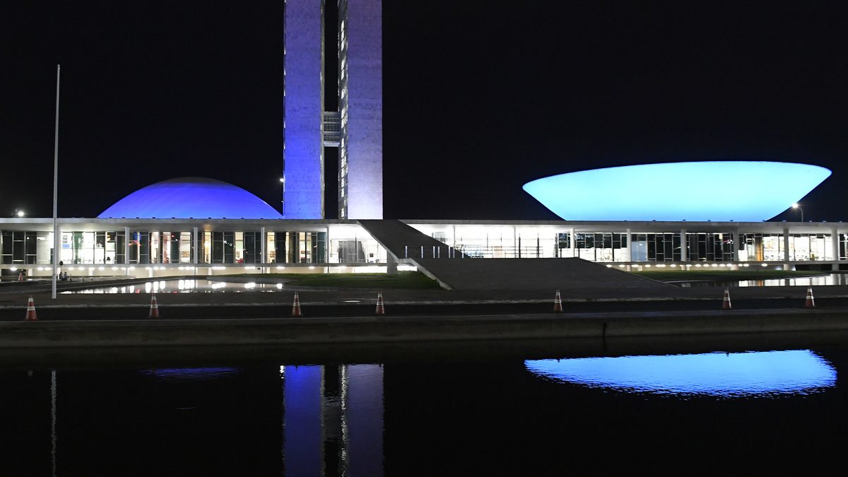 Cúpulas do Congresso Nacional iluminadas de azul à noite, em Brasília