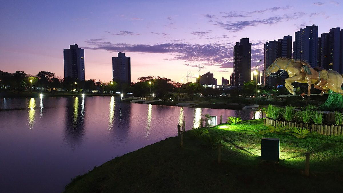 Lago do Parque das Nações Indígenas ao entardecer, com o Monumento ao Cavaleiro Guaicuru, em Campo Grande