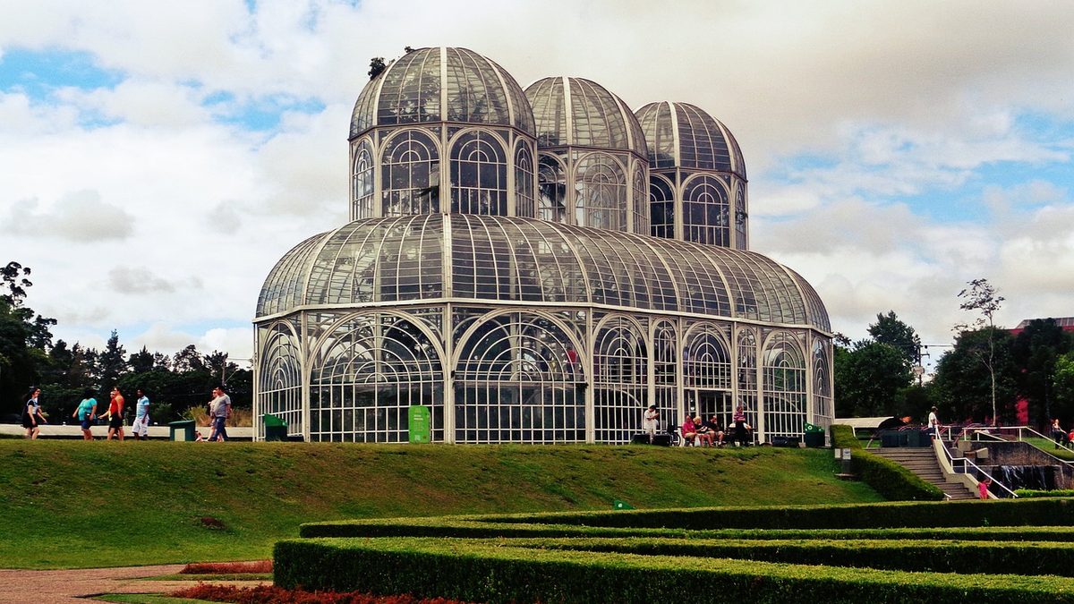 Estufa de vidro e ferro do Jardim Botânico de Curitiba, com jardins geométricos em primeiro plano