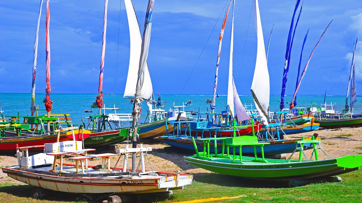 Jangadas coloridas com velas içadas na areia da praia da Pajuçara, em Maceió