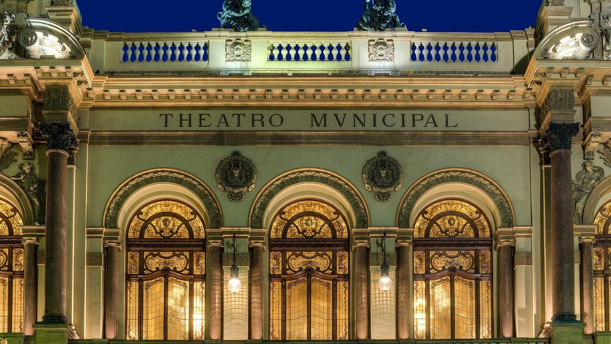 Fachada iluminada do Theatro Municipal de São Paulo, com o nome do teatro gravado no alto