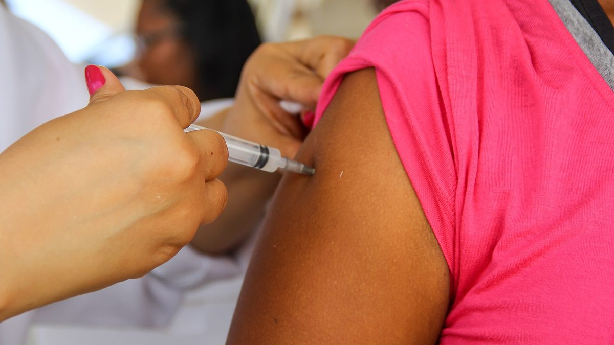 Profissional de saúde aplica vacina no braço de uma moradora em ação de saúde em Olinda