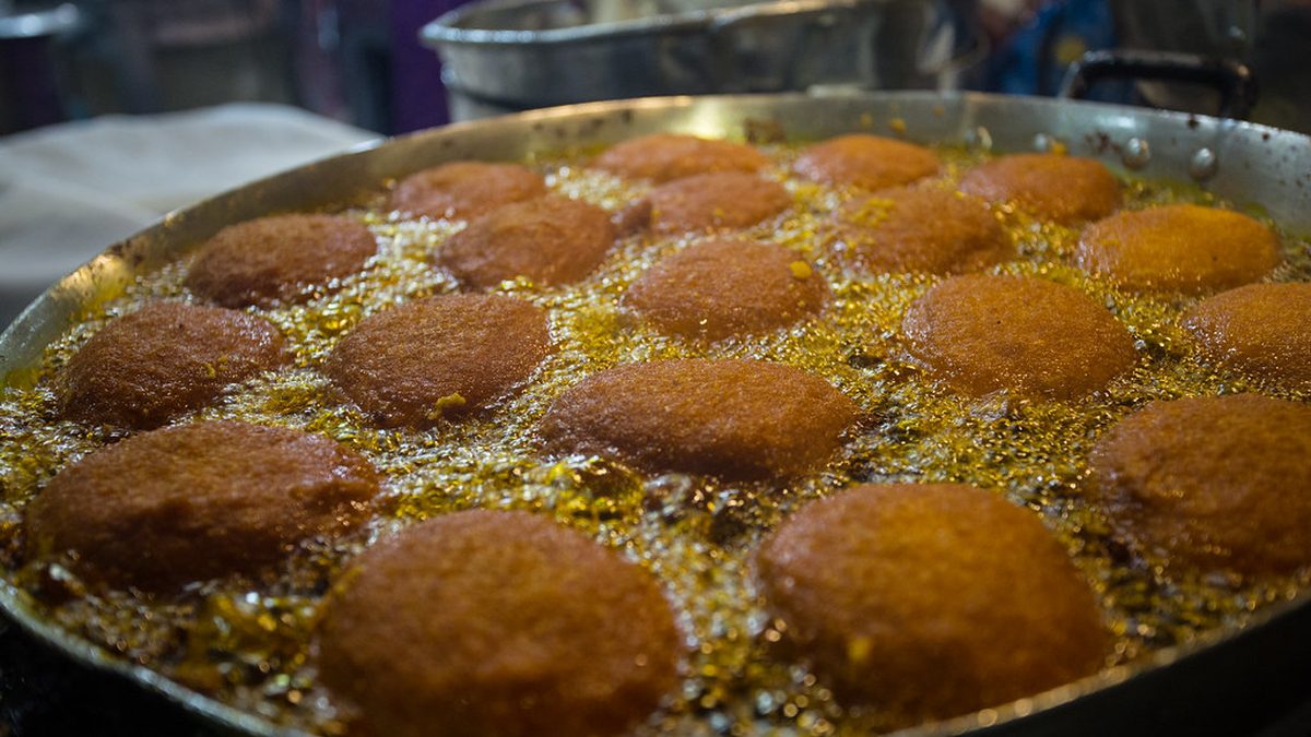 Bolinhos de acarajé fritando no azeite de dendê em tacho de tabuleiro