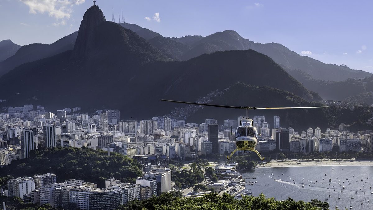 Helicóptero sobrevoa a enseada de Botafogo, com os prédios do bairro e o Corcovado ao fundo, no Rio