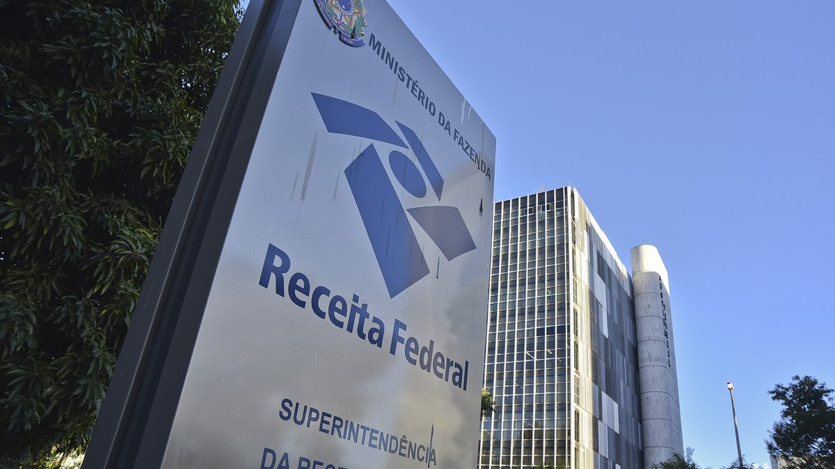 Placa da Receita Federal diante de prédio de escritórios