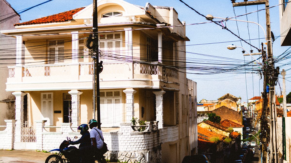 Casarão de dois andares e motociclistas em ladeira do centro histórico de São Luís