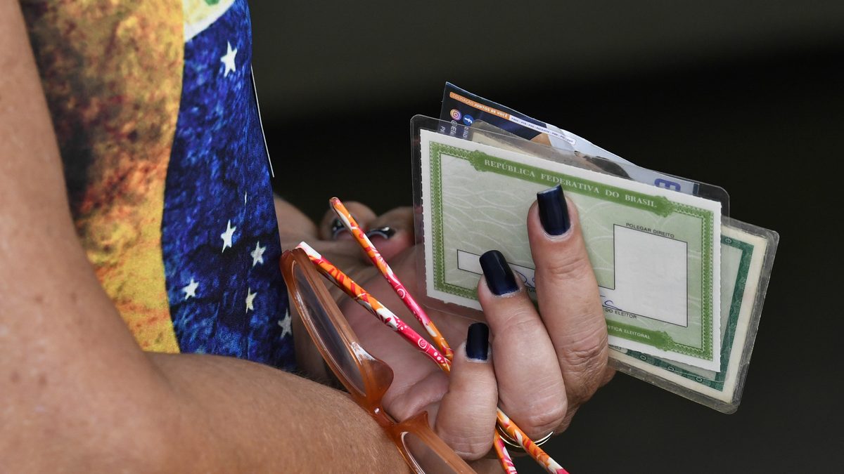 Eleitora segura o título de eleitor e a carteira de identidade