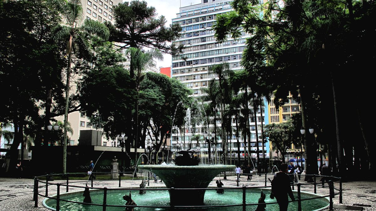 Chafariz cercado de árvores na Praça Osório, no Centro de Curitiba