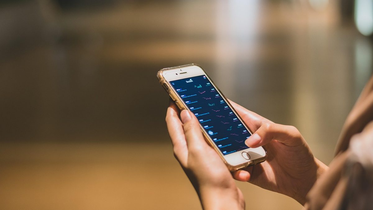 Mãos de uma pessoa consultando um aplicativo financeiro no celular