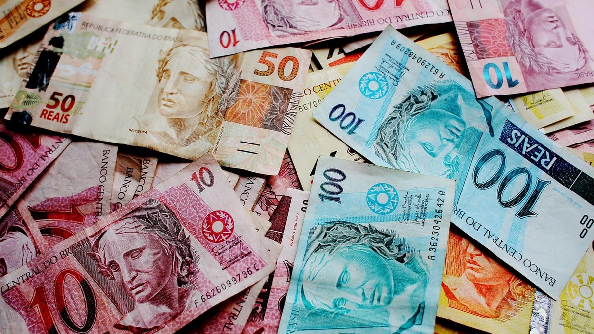 Cédulas de 10, 50 e 100 reais espalhadas sobre uma mesa