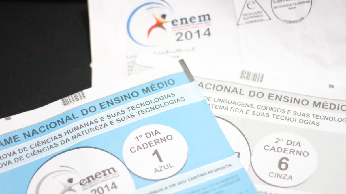 Cadernos de prova azul e cinza do Enem empilhados sobre uma mesa