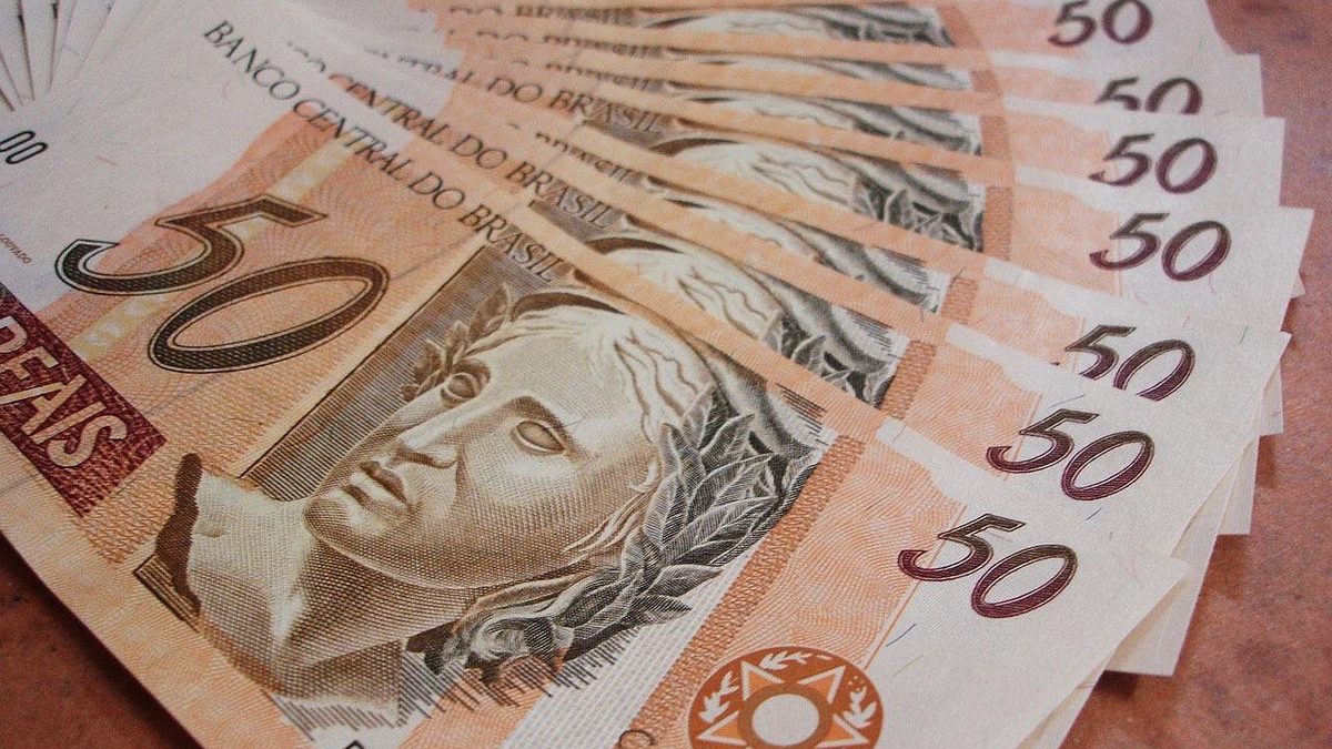 Cédulas de 50 reais abertas em leque sobre uma mesa