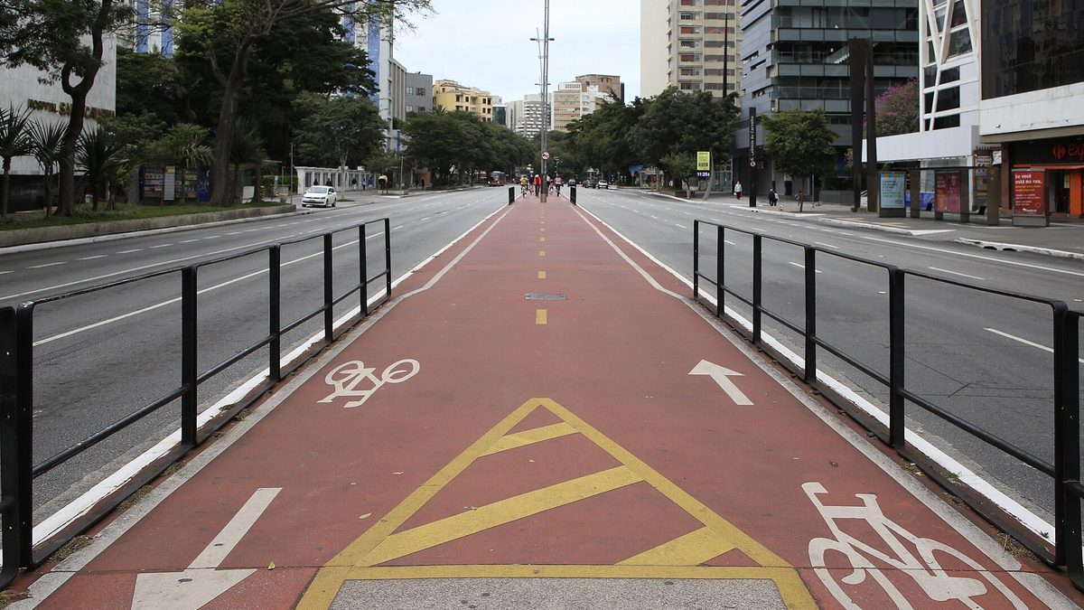 Ciclovia vermelha com sinalização de bicicleta no canteiro central de uma avenida de São Paulo