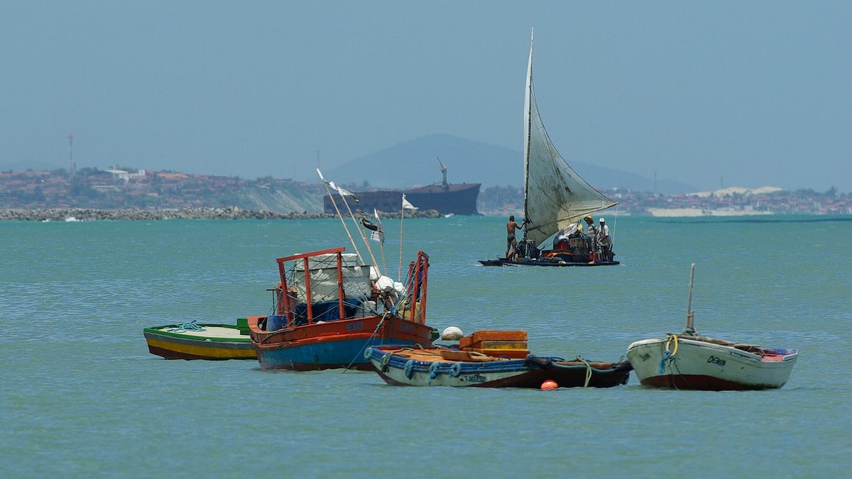 Barcos de pesca coloridos e uma jangada no mar do Mucuripe, em Fortaleza