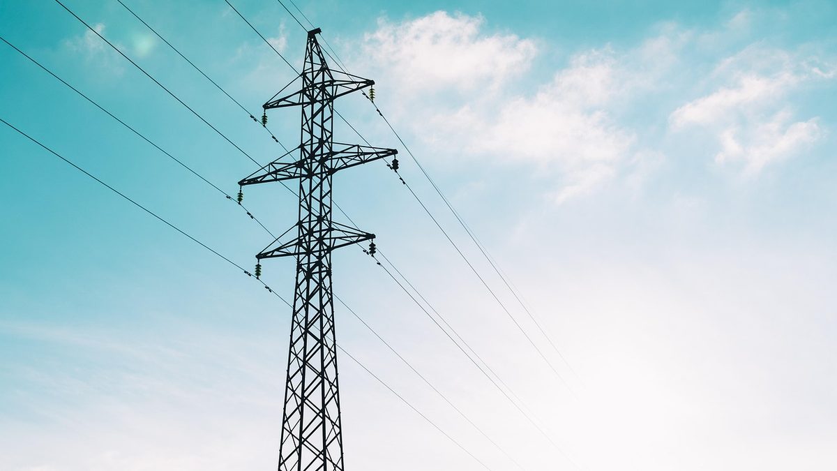 Torre de transmissão de energia elétrica com cabos, contra o céu azul