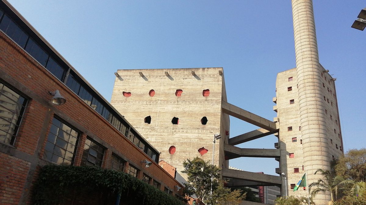 Torres de concreto do Sesc Pompeia e galpões de tijolo sob céu azul, em São Paulo