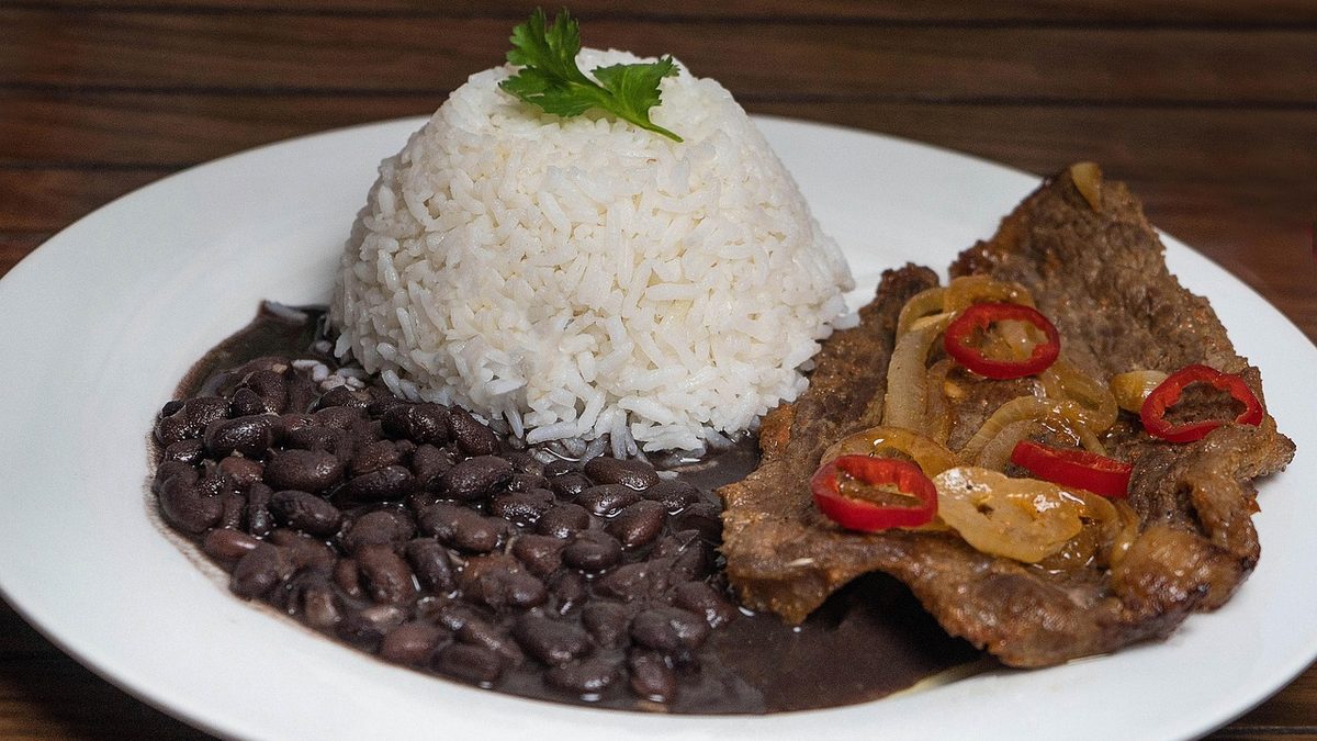 Prato feito com arroz branco, feijão preto e bife acebolado