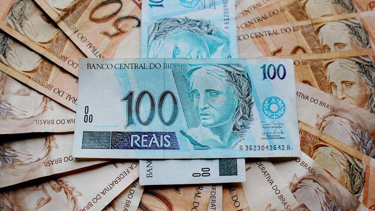 Cédula de 100 reais sobre um leque de notas de 50 reais