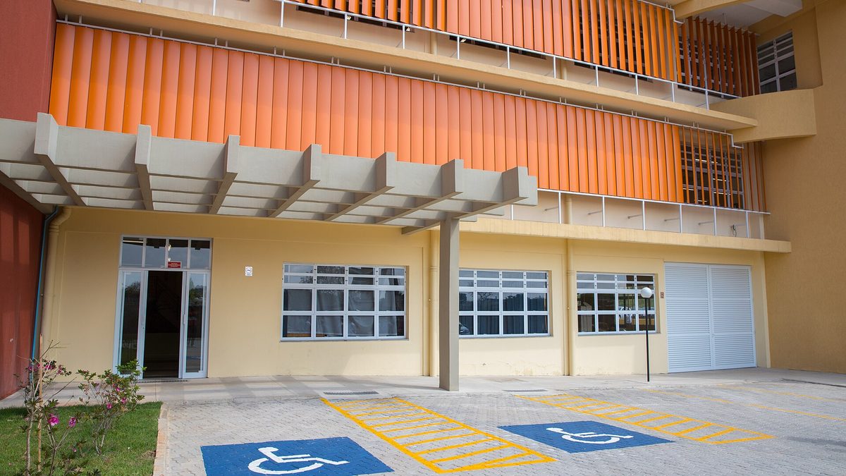 Fachada do prédio da Fatec e Etec de Guarulhos, com brises laranja e vagas para pessoas com deficiência